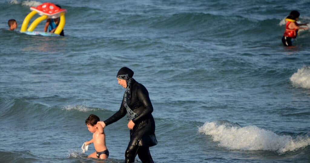 Cod vestimentar riguros pe plajele publice din Siria: Burkini obligatoriu pentru femei și tricouri pentru bărbați.