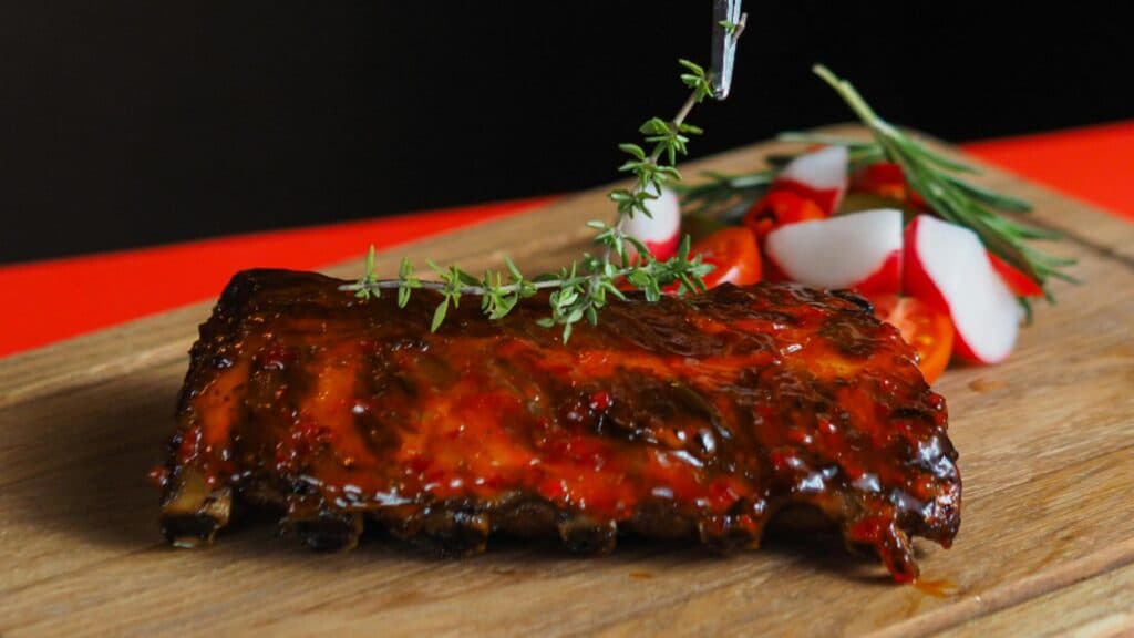 Coaste de porc caramelizate cu miere și sos barbecue, gătite la cuptor – deliciul ideal pentru o petrecere de Anul Nou